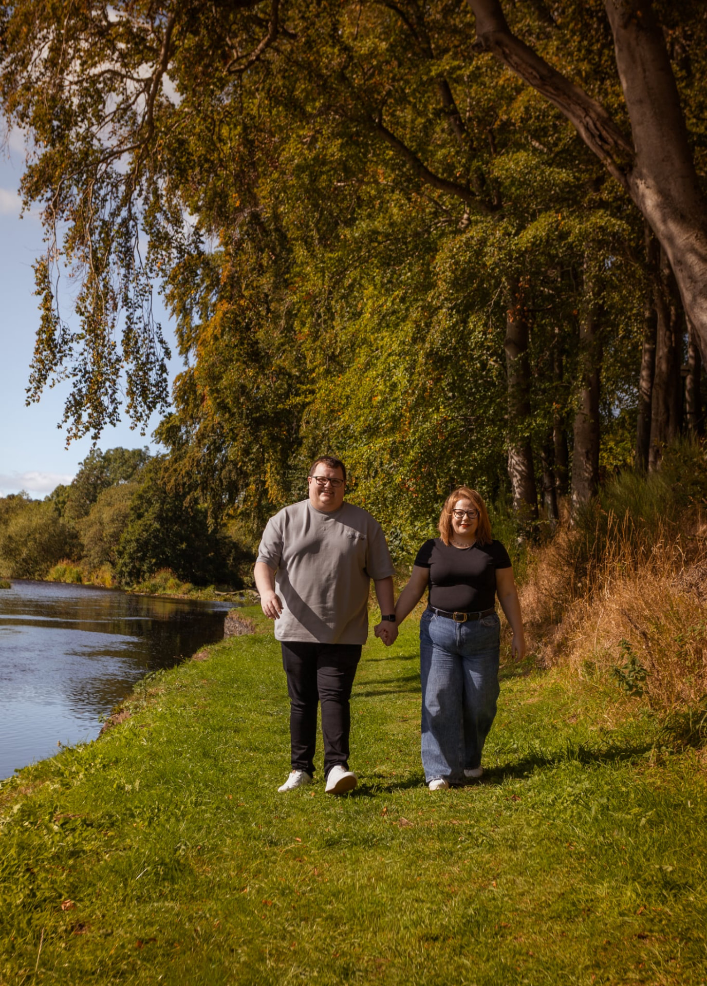 Couple walking hand in hand along a riverside path
